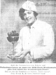 A woman in a white uniform, smiling into the camera while serving a confection.