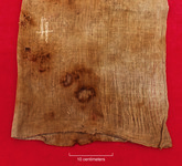 A photo of another cotton cloth that held maize. There is white repair yarn in the upper left and holes near the bottom left.