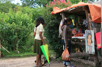Photograph of two women waiting for service at a small front-yard store made from off-cut timber and covered in tarpaulin.