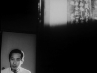 Black and white image with a mostly black screen. In the lower left corner is an image of a man, shoulders-up. In the top right corner is an abstract image with calligraphy.