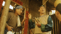 Two men talk in a doorway, framed by red calligraphic banners.