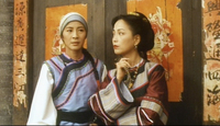 Two women stand in front of a doorway, framed by peeling calligraphic banners.