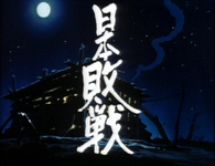 White calligraphy for "Japan Surrenders" is superimposed over a hovel at night.