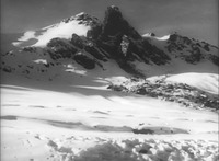 A mountain rises in a snow covered landscape.