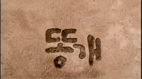 Brown calligraphy is carved out in the dirt.