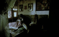 Image of a person sitting on a couch. The room is dark, but a plaque with a chinese character is visible on the wall
