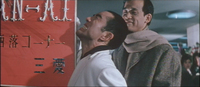 The protagonist Takeo is stabbed in the back as he holds on to a red signboard, which is adorned with extruded lettering in three styles and colors.