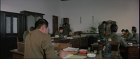 Men in an office work with banners on the wall with black calligraphy printed on them.