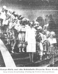A group of female dancers surrounding a woman in a white uniform.