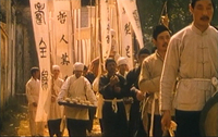 A crowd carries banners with black calligraphy printed on them.