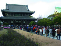 Fig. 1. A photograph of a line of visitors stretching from the right-foreground to a large temple building in the left-background. The path is fenced and lined by brown grass and a stretch of bare plants.