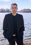 Photograph of Lefteris Kordis, standing by the water on a sunlit day.