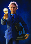 A figurine of Hannibal Lecter wearing a blue plaid three-­piece suit with a blue shirt and patterned tie. He holds a stag statue in his left hand and a glass of wine in his right. On his head is a pink flower crown.