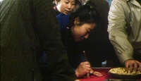 A woman brushes out characters on a red cloth to celebrate a wedding.
