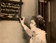 A woman holds a frame on the wall with white English text.