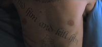 The chest of a man has English text tattooed across it.
