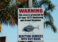 Photograph of a sign warning that the area is protected by 24-­hour CCTV monitoring and armed response.
