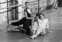 One dancer sitting, another crouching, the third kneeling. All alert, looking outside of the photo frame. Ballet barres behind.