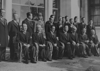 This black-­and-­white image shows Wang Jingwei, surrounded by an entourage of twenty-­one men, having a group photo taken in front of the Japanese Imperial Palace. Seven cushioned wicker armchairs are placed in the front row, with Wang seated in the middle. Dressed in a dark tuxedo, he looks solemn, downcast, and perhaps a little weary, placing his hands on both knees with his right shoulder slouching slightly forward. Chu Minyi, bald, looks at the carpeted floor. Zhou Fohai, bespectacled, raises his head to the left, in the direction of the camera. Other figures all look to the front, indicating another camera taking photos. Aside from two figures in the second and the third rows in military uniform, all are dressed in dark tuxedoes.