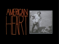 Orange English title in a handwritten style sits beside a vintage family photograph of father and son, all on a black background. They are block letters, with a small "American" above a tall "Heart", forming a block roughly the size of the adjacent photograph. The unique handwritten design is by Pablo Ferro, who first used this style for _Dr. Strangelove_.