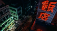 An overhead street view, with a red calligraphic neon sign prominently at the right side.