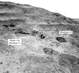 A photo of Quebrada 5-south. There are text boxes and arrows that indicate the location of Room 1 of Structure 11 on the left and Structure 12 on the right. There are a few men excavating the landscape.