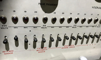 The mocked-­up control panel of a machine ostensibly designed to administer electric shocks. A horizontal row of lights and switches runs from left to right, between the 255 volts switch (marked “Intense Shock”) and the 435 volts switch (marked “XXX”).