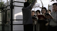 A group of readers at a gate hold signs with red, green and black calligraphy.