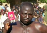 A shirtless man holds up a condom in a pink wrapper.