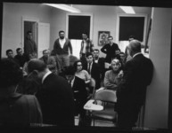 Black and white photo of a group of adult students in a small classroom space.