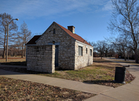 Fig. 121. Color photograph of an outdoor building of white and gray stones, with a red roof and boarded-­up windows. It is surrounded by trees and park sidewalks.