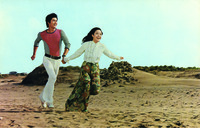 A shot from The Young Ones showing a man and a woman happily running on the beach.
