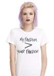 A model with pink hair and burgundy lipstick wears a white T-­shirt with black lettering that reads “My Fandom [is greater than] Your Fandom.”