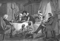 In a bright parlor room, several smiling family members sit around a table listening to an older man read a book.