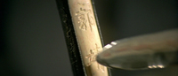 The name of the protagonist is carved into the handle of a sword with another sword.