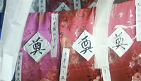 Black calligraphy on white paper is attached to colorful brocade fabric.