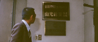 A person looks at a gold calligraphy sign as they pass through a doorway.