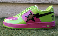 A lime green and fuchsia sneaker with a black shooting star across the side. There is a tiny image of the Hulk printed on the heel of the shoe.