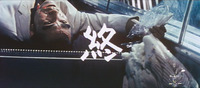 A film still of white calligraphic text over the background of a man lying on his back, with blood on his face.