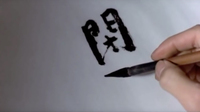 Black calligraphy being written on a white background.