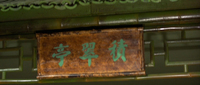 Calligraphy over a transom is painted in green, matching the color of the adjacent bamboo latticework.