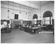 Photograph of the libray reading room at the Jewish Theological Seminary. Includes reading tables and exhibit case in front of fireplace.