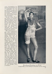 Black-and-white photograph of Josephine Baker featured in a German women’s magazine article about dance and eroticism; this depiction shows her in vaudeville pickaninny clothes: overalls with the legs asymmetrically folded up and a button-down top underneath. She stands with a leg angled out and both feet on the floor, left hand on her hip, and her right hand gesturing directly over her head. Her facial expression uses comic tropes: a small smile with crossed eyes. This image is large on the right side of the page with narrow German editorial text to the left.
