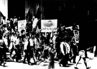 Fig. 4. Marchers, mostly men and a few women, holding signs reading “Gays Love God Loves Gays” and “Judge Not Lest Ye Be Judged.” One waving and one holding his fist in the air.