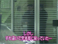 Color still of glass sliding doors at entrance to building. Behind lines painted on glass, figures of men visible. On screen, Japanese text reports that target (politician Murayama Tomiichi) has left and returned to another building. Alt.text: Color still. Image shows man and women in negative (colors reversed). In foreground, Japanese text reads: “Duet fail!!”