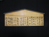 Photograph of a wooden board with black calligraphy.