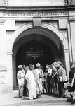 Several figures standing in front of an archway.