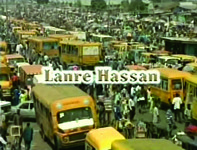 Film still frame of yellow buses stuck in a wide street filled with people