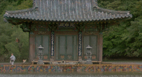 A building on a lake, with prominent calligraphy framing its door and board above.