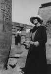 H.D. peers up at a stone structure with hieroglyphics carved into the surface. More stone structures are visible behind her.